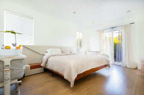 Bright master bedroom with king bed and balcony access for fresh air and natural light.