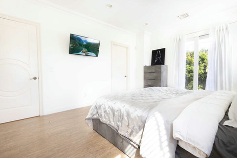 Alternate view of the bedroom highlighting the comfortable bed, dresser with mirror, and access to the private balcony