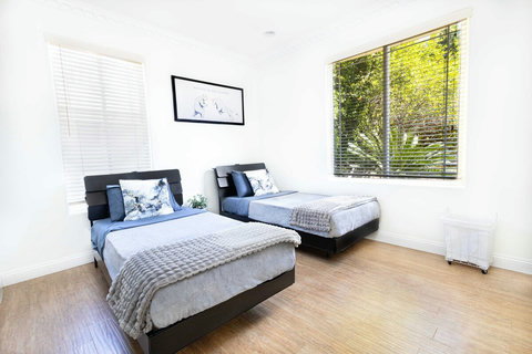 First floor guest room with two comfortable beds and views of the backyard dining and pool area.