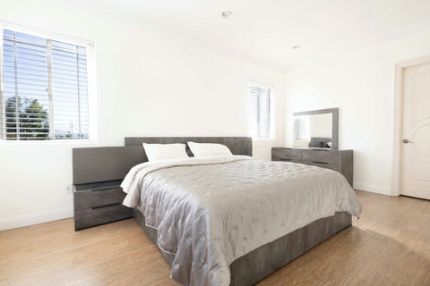 Spacious bedroom with a king size bed, clean modern furnishings, and large windows bringing in natural light.