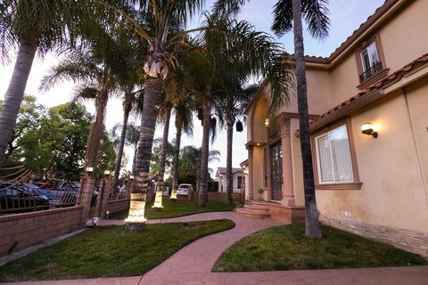 Welcoming front entrance lined with palm trees, soft landscape lighting, and a curved walkway leading up to the home.