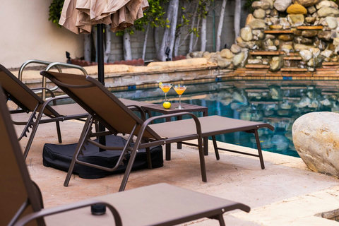 Comfortable sun loungers set beside the pool with umbrella shade and a small table for drinks.