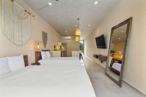 Bright room with two cozy beds, boho décor, a full kitchen, smart TV, and a private balcony with lush views.