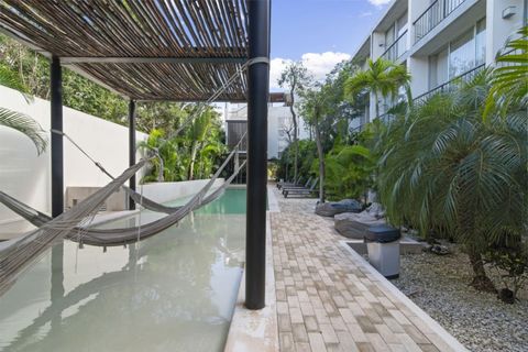 Relax in the hammock lounge over shallow water, surrounded by lush greenery and a peaceful shared pool area—perfect for a laid-back afternoon in Tulum.