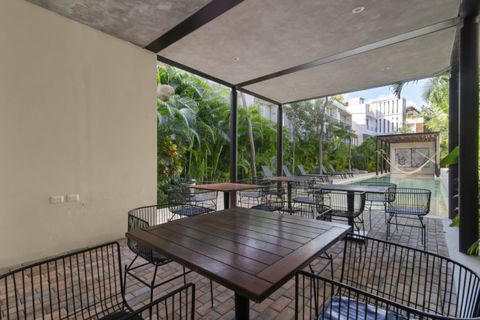 Covered outdoor dining area by the pool with wooden tables, modern black chairs, and lush tropical surroundings—perfect for meals or drinks with a view.