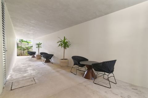 Shaded common area with modern black chairs, small tables, and potted plants—perfect for reading, relaxing, or enjoying a quiet moment outdoors.