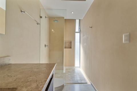 Bright full bathroom with a spacious walk-in rain shower, modern glass partition, marble countertop, and natural light for a fresh and relaxing atmosphere.