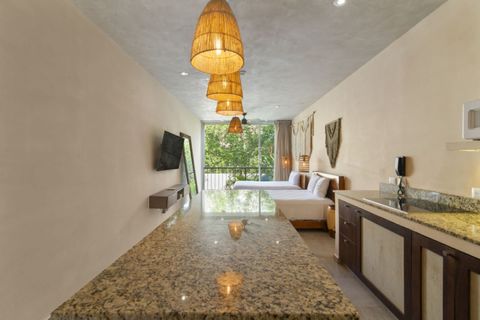 Open studio with granite island, pendant lights, Smart TV, king bed, and balcony with jungle views,  bright, cozy, and perfect for relaxing.