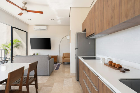 Bright open-concept kitchen and living area with sleek wood cabinetry, marble floors, and large windows that fill the space with natural light—perfect for relaxing or sharing meals with loved ones.
