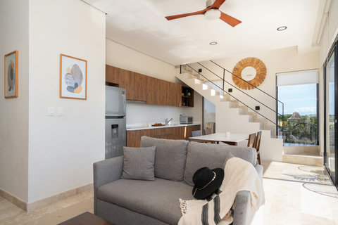 Bright living room with an open kitchen, natural light, and warm wooden finishes creating a cozy and modern atmosphere to relax or enjoy meals together.
