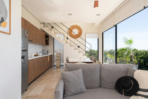 Spacious living area with an integrated kitchen, elegant design, and floor-to-ceiling windows that bring nature indoors.