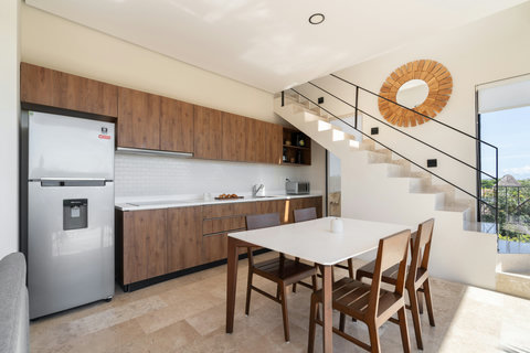 Modern kitchen with warm wood cabinetry, sleek finishes, and a bright dining area for four—ideal for sharing meals in a calm and elegant setting.