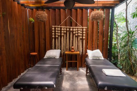 Relaxing massage area with two spa beds, soft lighting, and a rustic wooden backdrop, creating a serene oasis for ultimate relaxation.
