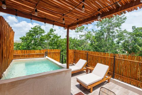 Relaxing rooftop retreat with a refreshing plunge pool, cozy lounge chairs, and a rustic bamboo fence, creating a serene tropical vibe.