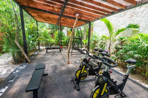 Tropical fitness area with spin bikes, weight benches, and functional training gear under a wooden pergola, blending nature and exercise.