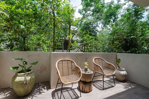 Cozy private balcony with woven chairs, a rustic wooden table, and lush greenery for a peaceful retreat. A perfect spot to relax and enjoy nature.