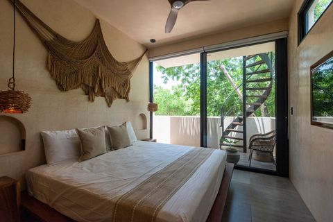 Elegant bedroom with a cozy boho design, king-size bed a wall-mounted TV, and warm rattan lighting. A balcony features a spiral staircase leading up to a private rooftop terrace.