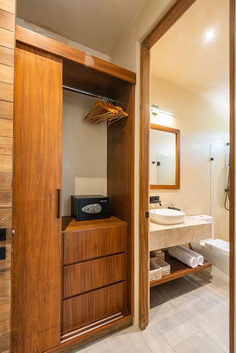 Modern full bathroom with a sleek walk-in shower, rainfall showerhead, and glass partition. Features a stylish stone countertop, vessel sink, and warm wood accents for a minimalist, elegant look