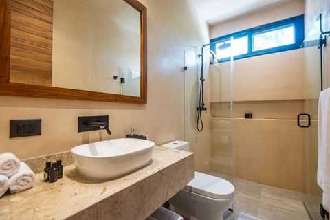 Elegant full bathroom with a spacious walk-in shower, rainfall showerhead, and glass partition. Features a sleek stone countertop, vessel sink, and wooden-framed mirror for a warm, modern touch.
