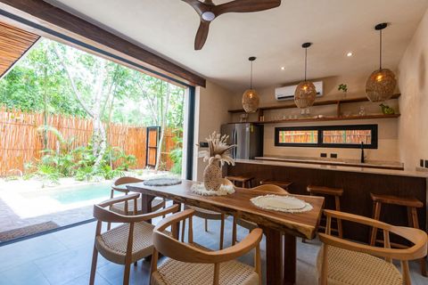 Seamless indoor-outdoor living with a dining area overlooking a lush tropical patio. Natural wood tones, woven textures, and warm lighting enhance the inviting atmosphere.