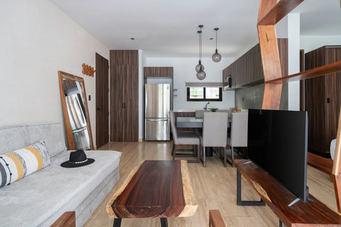 This living space features a cozy sofa, TV, and coffee table, with direct access to a private patio. Ideal for relaxing, enjoying fresh air, or spending quality time in a peaceful setting.