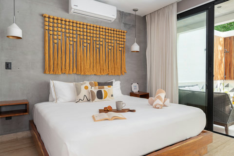 Spacious bedroom with a comfortable king-size bed and air conditioning, featuring direct access to the private patio. Perfect for relaxing, resting, and enjoying a serene outdoor space