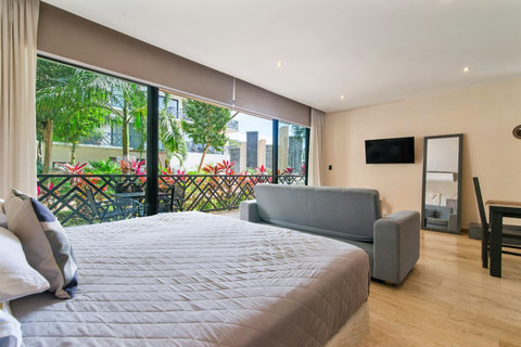 Bright living space with a king bed, cozy sofa, and floor-to-ceiling windows. Lush garden views, modern decor, and soft lighting create a relaxing and inviting atmosphere.