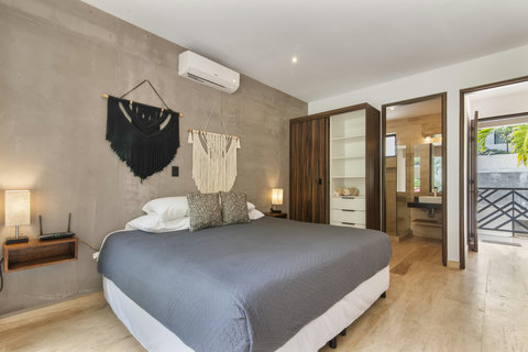 This modern bedroom offers a king-size bed, stylish macramé wall art, and a spacious wardrobe. With a private bathroom and a view to a serene garden, it's your perfect escape.