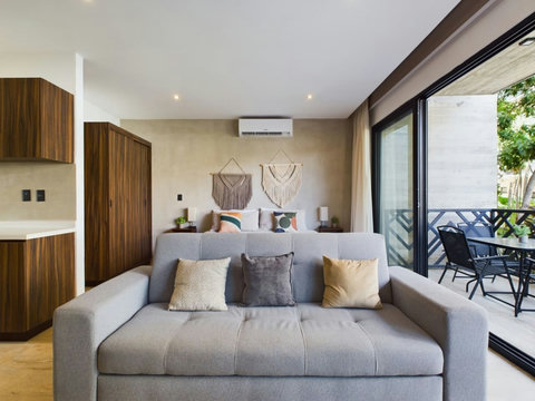 Unwind in a stylish space with a cozy gray sofa, elegant king bed, and boho macramé accents. Floor-to-ceiling windows open to a private balcony, flooding the room with natural light.