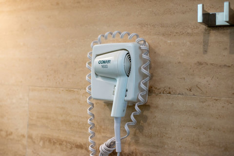 Wall-mounted hairdryer, perfect for added convenience in the bathroom for guests who need to style their hair during their stay.