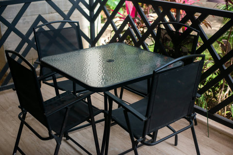 The private terrace features a glass-top dining table with four comfortable chairs, perfect for enjoying meals or relaxing outdoors surrounded by lush greenery.