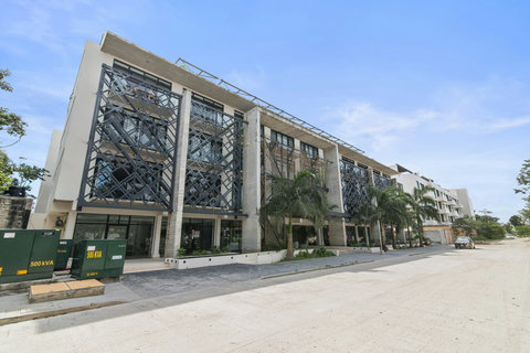Modern apartment building with a sleek architectural design, featuring decorative metal panels and lush palm trees. A prime location offering contemporary living in a stylish and well-maintained setting.