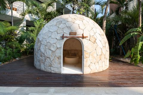 Traditional stone temazcal nestled in a tropical garden, offering a unique wellness experience with natural surroundings and a peaceful vibe.