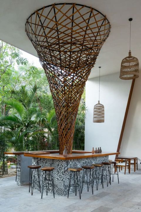 Unique open-air bar with a striking woven bamboo structure, patterned tile base, and high stools. Surrounded by lush greenery, it's a perfect tropical social spot.