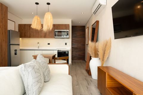 Stylish studio with a full kitchen, cozy sofa, TV, wooden furniture, and warm neutral decor. Includes pendant lighting, AC, and natural touches like pampas grass and a full-length mirror.