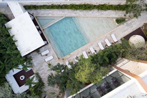 Aerial view of a serene pool area with lounge chairs, shaded beds, tropical trees, and a temazcal. A perfect space to unwind and enjoy the peaceful Tulum atmosphere.