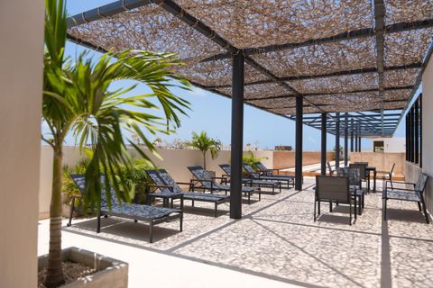 Embrace the allure of Palais Tulum's delightful terrace, featuring inviting chairs and tables ideal for relaxation and relishing the sun's warmth, a peaceful oasis for serene moments.