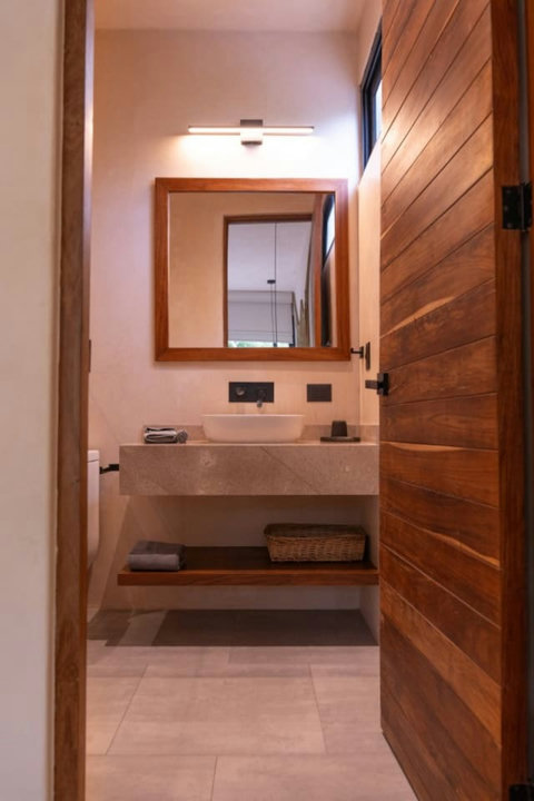 Stylish half bath. Features a sleek stone vanity, a modern vessel sink, warm wooden accents, and soft lighting—perfectly designed for comfort and elegance.