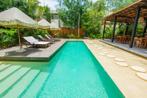 Tropical poolside escape. Enjoy a stunning swimming pool surrounded by lush greenery, comfy lounge chairs, and shaded areas—perfect for relaxation.