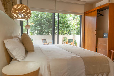 Bright and airy bedroom. Enjoy natural light, a comfortable bed, and lush green views from the large windows—perfect for a restful stay.