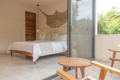 Cozy bedroom with a private balcony. Features a plush king-size bed, soft lighting, and floor-to-ceiling windows that open to a peaceful outdoor space