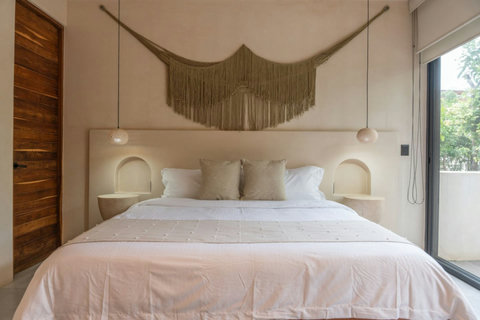 Elegant and serene bedroom. A stylish king-size bed with built-in lighting, boho macramé décor, and soft neutral tones create a relaxing atmosphere.