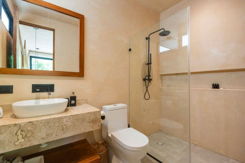 Modern full bathroom with a sleek walk-in shower, rainfall showerhead, and glass partition. Features a stylish stone countertop, vessel sink, and warm wood accents for a minimalist, elegant look