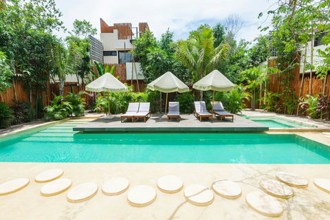 Resort-style pool area. Featuring elegant sunbeds, large umbrellas, and a serene jungle backdrop—ideal for unwinding in paradise.