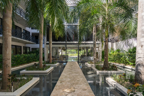Tropical courtyard with palm trees, water features, and garden paths—a serene retreat ideal for a morning walk or peaceful relaxation.