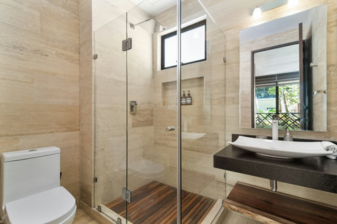 Elegant bathroom with a glass-enclosed rain shower, natural stone finishes, and a stylish vessel sink—designed for a refreshing and relaxing experience.