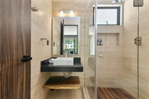Modern bathroom with sleek finishes, a rainfall shower, elegant stone walls, and a stylish vessel sink. Thoughtfully designed for a spa-like experience during your stay.