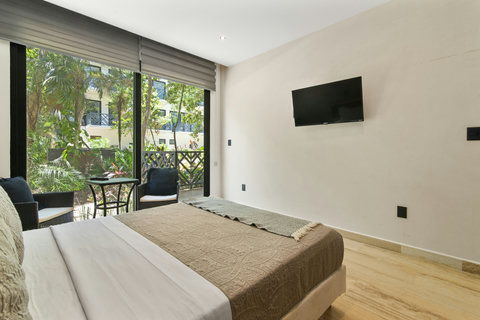 Wake up to lush garden views in this bright bedroom with a king-size bed, cozy linens, wall-mounted TV, and direct access to a private terrace—perfect for morning coffee or evening relaxation.