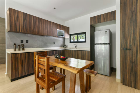 Modern fully-equipped kitchen with wood finishes, stainless steel fridge, and cozy dining area — perfect for long stays in Tulum. Bright, stylish, and functional!