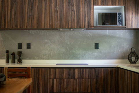 Sleek kitchenette with modern wood cabinets, built-in microwave, and minimalist décor—perfect for prepping light meals in style during your Tulum stay.